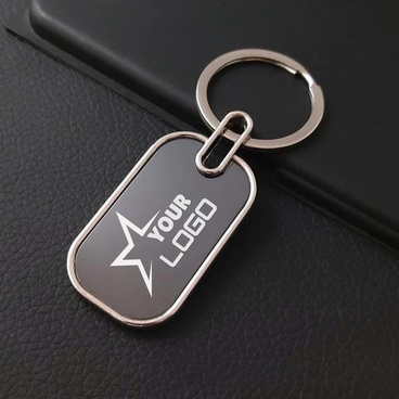 Engraved metal keychain with a custom logo on a leather surface